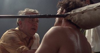 Movie still from “Fat City” (1972), directed by John Huston – A man is holding a sword in front of a mirror; Close Up shot, Over the shoulder angle