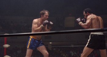 Movie still from “Fat City” (1972), directed by John Huston – A man wearing boxing gloves and a blue and yellow shorts; Medium shot, Low angle