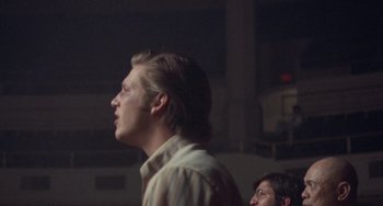 Movie still from “Fat City” (1972), directed by John Huston – A man standing in front of another man in a dark room; Close Up shot, Low angle