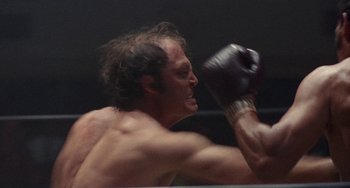 Movie still from “Fat City” (1972), directed by John Huston – A man with no shirt is boxing in a boxing ring; Close Up shot, Low angle