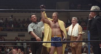 Movie still from “Fat City” (1972), directed by John Huston – A man in a boxing ring holding up a glove; Medium shot, Low angle