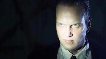 Movie still from “Father's Day” (2011), directed by Conor Sweeney – A person wearing a suit and tie; Close Up shot, Low angle