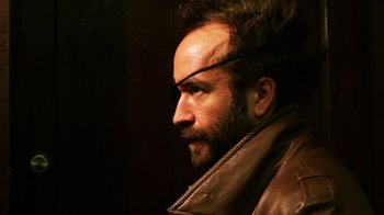 Movie still from “Father's Day” (2011), directed by Conor Sweeney – A bearded man wearing a leather jacket and a headband; Close Up shot, Low angle