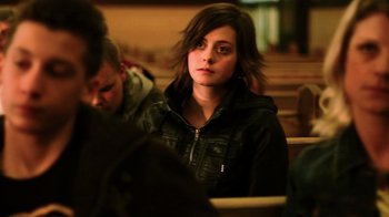 Movie still from “Father's Day” (2011), directed by Conor Sweeney – A woman sitting on a bench in a room; Close Up shot, Over the shoulder angle