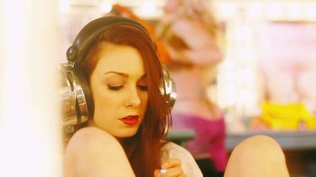 Movie still from “Father's Day” (2011), directed by Conor Sweeney – A beautiful young woman wearing headphones while holding a cell phone to her ear; Close Up shot, Over the shoulder angle