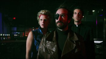 Movie still from “Father's Day” (2011), directed by Conor Sweeney – A group of people standing next to each other in a dark room; Medium shot, Low angle