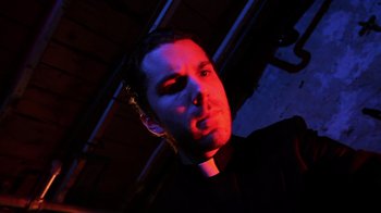 Movie still from “Father's Day” (2011), directed by Conor Sweeney – A man wearing a priest's outfit with red light shining on his face; Close Up shot, Low angle