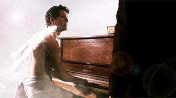 Movie still from “Father's Day” (2011), directed by Conor Sweeney – A man sitting in front of an upright piano; Medium shot, Low angle