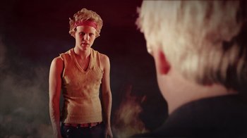 Movie still from “Father's Day” (2011), directed by Conor Sweeney – A woman standing in front of a mirror in front of a wall; Medium shot, Over the shoulder angle
