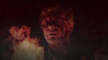 Movie still from “Father's Day” (2011), directed by Conor Sweeney – A man with glasses is in the middle of a fire; Close Up shot, Low angle