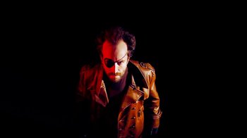 Movie still from “Father's Day” (2011), directed by Conor Sweeney – A man wearing a brown leather jacket and a pair of sunglasses; Medium shot, Low angle
