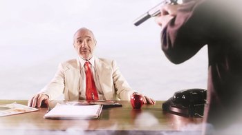 Movie still from “Father's Day” (2011), directed by Conor Sweeney – An older man sitting at a table in front of an apple; Medium shot, High angle