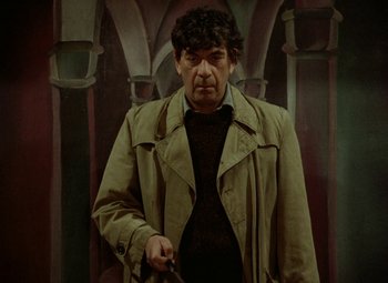 Movie still from “Faust” (1994), directed by Jan Svankmajer – A man in a trench coat is standing in front of an archway; Medium shot, Low angle