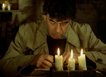 Movie still from “Faust” (1994), directed by Jan Svankmajer – A man lighting candles on top of a wooden table; Medium shot, High angle