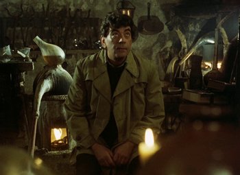 Movie still from “Faust” (1994), directed by Jan Svankmajer – A man sitting in front of a fireplace with candles; Medium shot, Over the shoulder angle