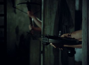 Movie still from “Faust” (1994), directed by Jan Svankmajer – A person holding a crossbow in their hand; Medium shot, Over the shoulder angle