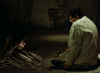 Movie still from “Faust” (1994), directed by Jan Svankmajer – A man sitting on the ground looking at another man; Wide shot, High angle