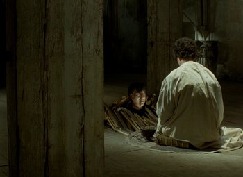 Movie still from “Faust” (1994), directed by Jan Svankmajer – A man sitting on the ground next to another man; Wide shot, High angle