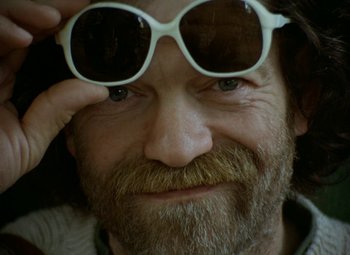 Movie still from “Faust” (1994), directed by Jan Svankmajer – An old man with a beard and a mustache wearing sunglasses; Extreme Close Up shot, Low angle