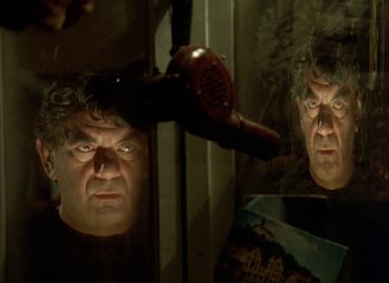 Movie still from “Faust” (1994), directed by Jan Svankmajer – A man with a blow dryer in front of a mirror; Close Up shot, Low angle