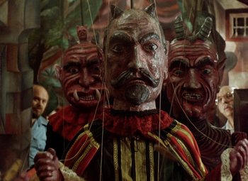 Movie still from “Faust” (1994), directed by Jan Svankmajer – A man standing next to a bunch of wooden puppets; Medium shot, Low angle