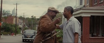 Movie still from “Fences” (2016), directed by Denzel Washington – Two men standing next to each other on the street; Medium shot, Over the shoulder angle