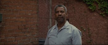 Movie still from “Fences” (2016), directed by Denzel Washington – A man standing in front of a brick building; Close Up shot, Over the shoulder angle