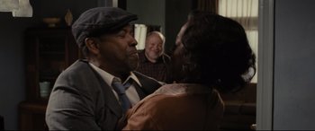 Movie still from “Fences” (2016), directed by Denzel Washington – A man and a woman are kissing in front of another man; Medium shot, Over the shoulder angle