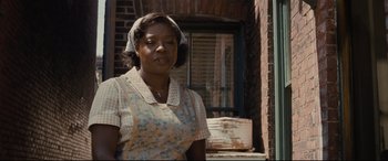 Movie still from “Fences” (2016), directed by Denzel Washington – An older woman standing in front of a brick building; Medium shot, Low angle
