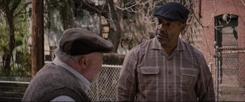 Movie still from “Fences” (2016), directed by Denzel Washington – Two older men standing next to each other in front of a fence; Medium shot, Over the shoulder angle