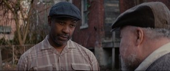 Movie still from “Fences” (2016), directed by Denzel Washington – A man wearing a hat standing in front of a brick building; Close Up shot, Over the shoulder angle