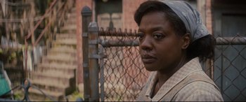Movie still from “Fences” (2016), directed by Denzel Washington – A woman standing in front of a chain link fence; Close Up shot, Over the shoulder angle