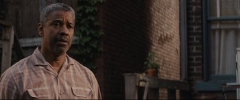 Movie still from “Fences” (2016), directed by Denzel Washington – A man standing in front of a brick building; Close Up shot, Over the shoulder angle