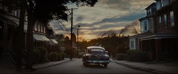 Movie still from “Fences” (2016), directed by Denzel Washington – An old car driving down a street at sunset; Extreme Wide shot, Over the shoulder angle