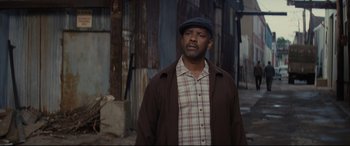 Movie still from “Fences” (2016), directed by Denzel Washington – A man wearing a hat standing in front of a building; Medium shot, Low angle