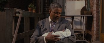 Movie still from “Fences” (2016), directed by Denzel Washington – A man in a suit and tie holding a baby; Close Up shot, Over the shoulder angle