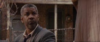 Movie still from “Fences” (2016), directed by Denzel Washington – A man in a suit and tie in front of a brick building; Close Up shot, Low angle
