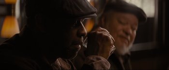 Movie still from “Fences” (2016), directed by Denzel Washington – A man with a hat is holding a drink; Close Up shot, Over the shoulder angle