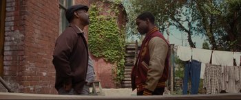 Movie still from “Fences” (2016), directed by Denzel Washington – Two men standing next to each other in front of a building; Medium shot, Over the shoulder angle