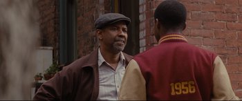 Movie still from “Fences” (2016), directed by Denzel Washington – A man wearing a hat talking to another man; Close Up shot, Over the shoulder angle