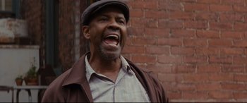 Movie still from “Fences” (2016), directed by Denzel Washington – A man with a hat and a beard is standing outside; Close Up shot, Low angle