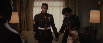 Movie still from “Fences” (2016), directed by Denzel Washington – A man in a military uniform holding hands with a woman in front of a window; Medium shot, Over the shoulder angle