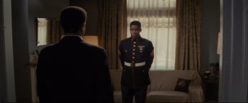 Movie still from “Fences” (2016), directed by Denzel Washington – A man in a uniform standing next to another man in front of a window; Medium shot, Over the shoulder angle