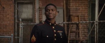 Movie still from “Fences” (2016), directed by Denzel Washington – A man in a military uniform standing in front of a brick building; Close Up shot, Over the shoulder angle