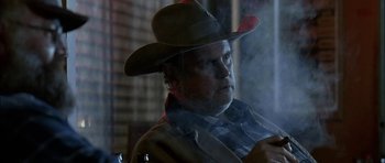 Movie still from “Fire in the Sky” (1993), directed by Robert Lieberman – A man wearing a cowboy hat smoking a cigarette; Close Up shot, Low angle