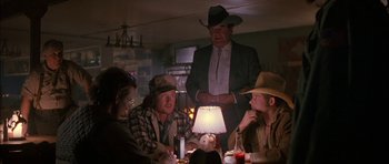 Movie still from “Fire in the Sky” (1993), directed by Robert Lieberman – A group of men sitting at a table with a lamp; Medium shot, Over the shoulder angle