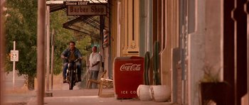 Movie still from “Fire in the Sky” (1993), directed by Robert Lieberman – Two men on a motorcycle in front of a barber shop; Wide shot, Low angle