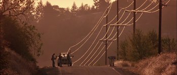 Movie still from “Fire in the Sky” (1993), directed by Robert Lieberman – Three people standing next to a car on the side of the road; Extreme Wide shot, Low angle