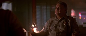 Movie still from “Fire in the Sky” (1993), directed by Robert Lieberman – A man in uniform holding a cup of coffee in a dimly - lit room; Close Up shot, Low angle