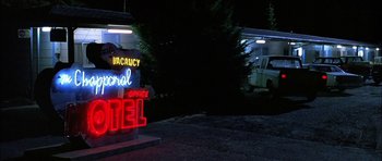 Movie still from “Fire in the Sky” (1993), directed by Robert Lieberman – A motel sign lit up at night with a van in the background; Wide shot, Low angle